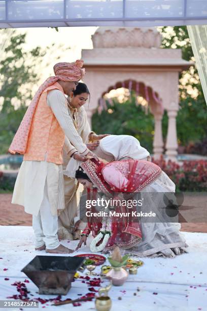 le couple de jeunes mariés cherche les bénédictions des membres âgés de la famille en touchant leurs pieds après la cérémonie de mariage - bénédiction photos et images de collection