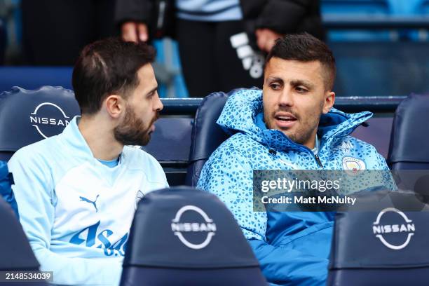 Rodri of Manchester City speaks with Bernardo Silva on the substitutes bench prior to the Premier League match between Manchester City and Luton Town...