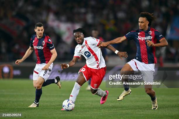 Warren Bondo of AC Monza runs with the ball whilst under pressure from Remo Freuler and Joshua Zirkzee of Bologna FC during the Serie A TIM match...