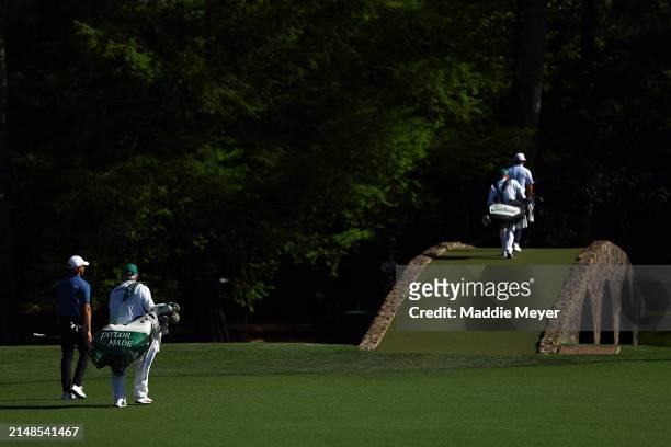 Tommy Fleetwood of England and Cameron Smith of Australia walk across the Hogan Bridge on the 12th hole during the third round of the 2024 Masters...