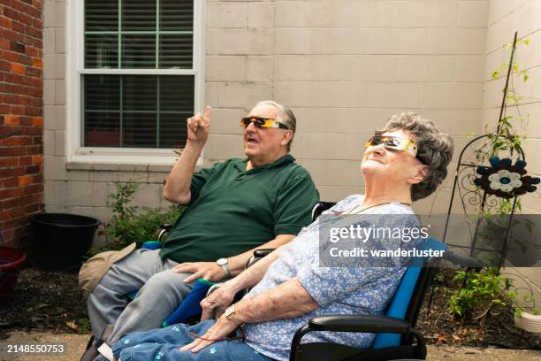 two senior adults in wheelchairs prepare to watch the total solar eclipse - zonsverduistering stockfoto's en -beelden