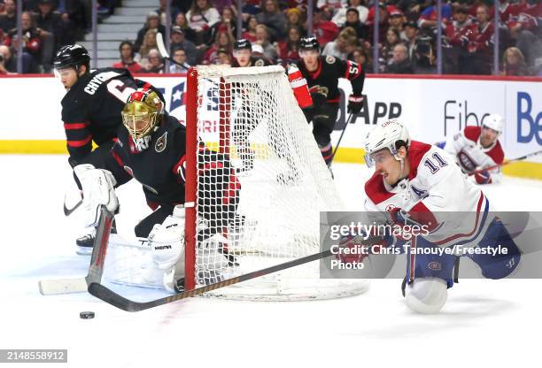 Brendan Gallagher of the Montreal Canadiens makes a diving play to pass the puck in front of Joonas Korpisalo of the Ottawa Senators net during the...