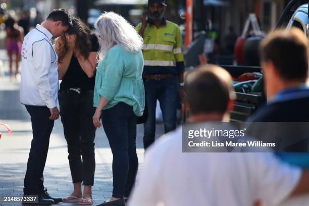 Woman is comforted after laying a floral tribute at Oxford Street Mall alongside Westfield Bondi Junction on April 14, 2024 in Bondi Junction,...