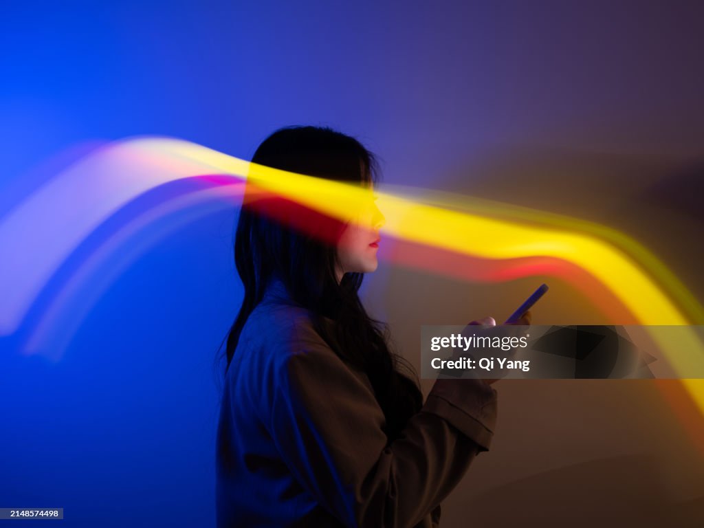 Business woman using smartphone at night. Glow stick long exposure