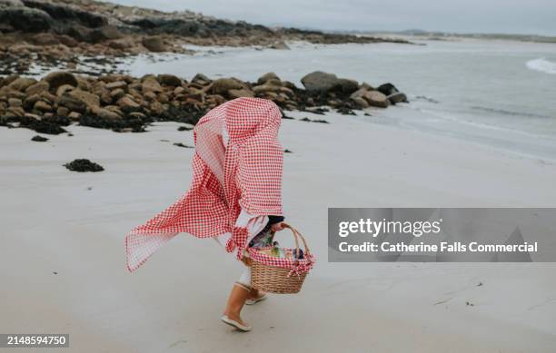 an optimistic child attempts to have a picnic on a beach on a windy day - weather forecaster stock pictures, royalty-free photos & images