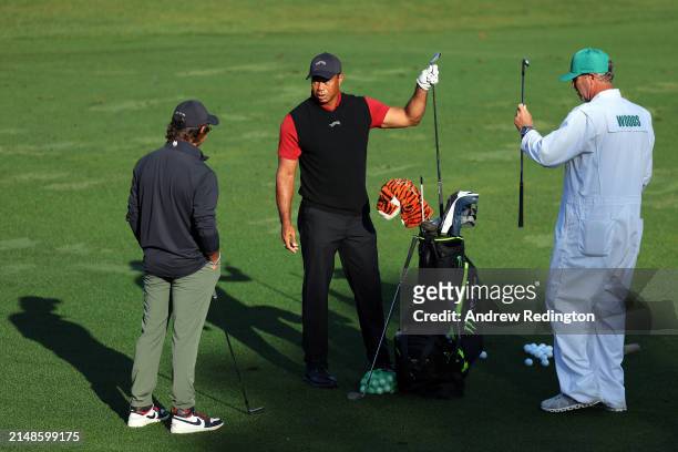Tiger Woods of the United States warms up in the practice area as his caddie Lance Bennett and son Charlie Woods looks on during the final round of...