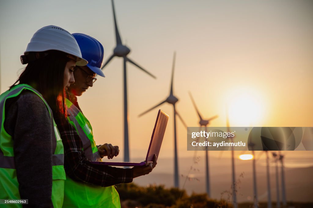 Springtime Engineer Young Maintenance Engineer Team Working In Wind Turbine Farm At Sunset ...