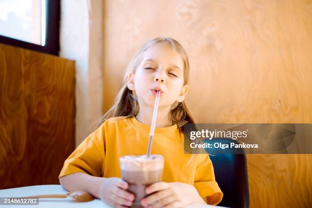a cute young girl enjoys a chocolate milkshake - chocolate shake stock pictures, royalty-free photos & images