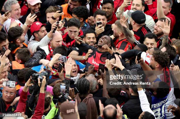 Jeremie Frimpong of Bayer Leverkusen celebrates with fans who have invaded the pitch after the team's victory and winning the Bundesliga title for...