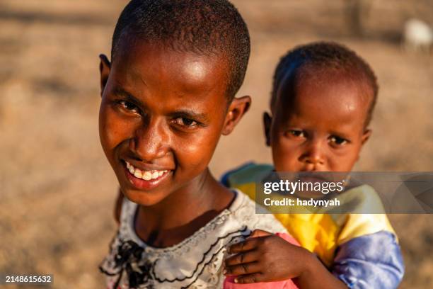 african little girl carrying a baby girl, kenya, africa. - east african tribe stock pictures, royalty-free photos & images