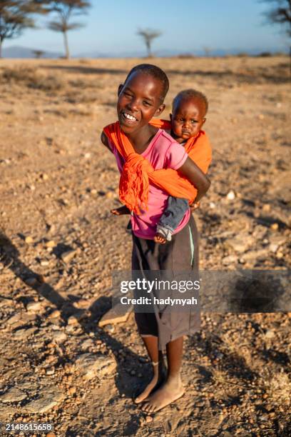 african little girl carrying a baby girl, kenya, africa. - east african tribe stock pictures, royalty-free photos & images