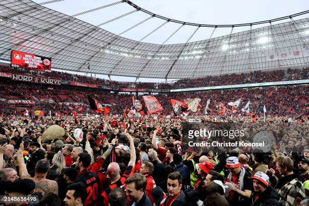 Fans of Bayer Leverkusen invade the pitch and celebrate after their team's victory and winning the Bundesliga title for the first time in their...