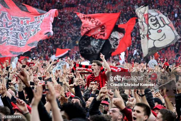 Fans of Bayer Leverkusen invade the pitch and celebrate after their team's victory and winning the Bundesliga title for the first time in their...