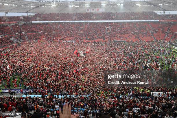 Fans of Bayer 04 Leverkusen invade the pitch after their team's victory and winning the Bundesliga title for the first time in their history in the...