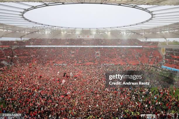 Fans of Bayer 04 Leverkusen invade the pitch after their team's victory and winning the Bundesliga title for the first time in their history in the...