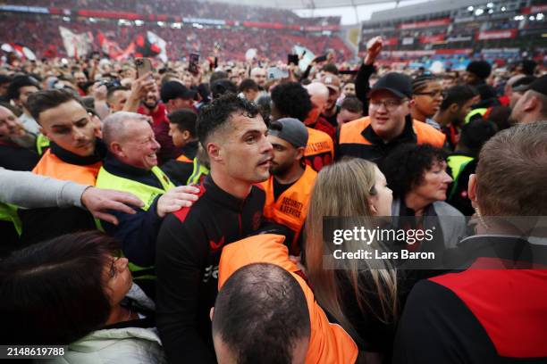 Granit Xhaka of Bayer Leverkusen celebrates with fans who have invaded the pitch after the team's victory and winning the Bundesliga title for the...