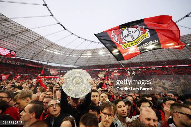 Flags displayed by fans of Bayer Leverkusen are seen as they invade the pitch and celebrate after their team's victory and winning the Bundesliga...