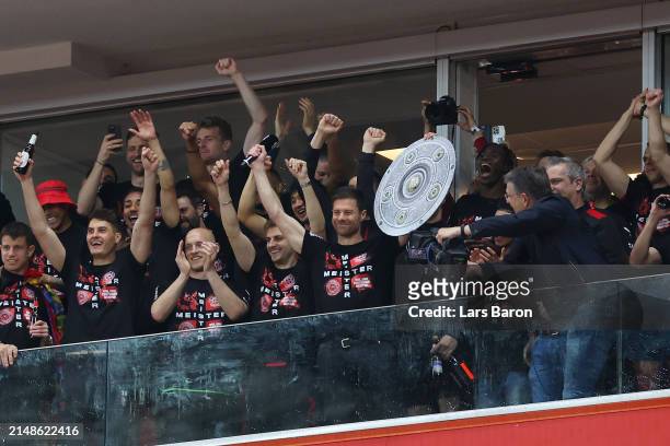 Xabi Alonso, Head Coach of Bayer Leverkusen, celebrates with a replica trophy alongside players after their team's victory and winning the Bundesliga...