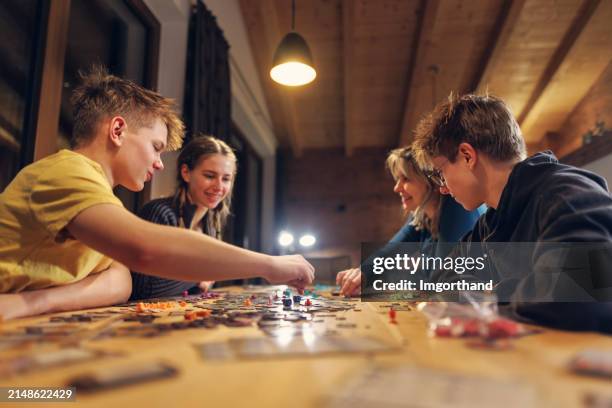 family playing large modern board game together at home - juegos fotografías e imágenes de stock
