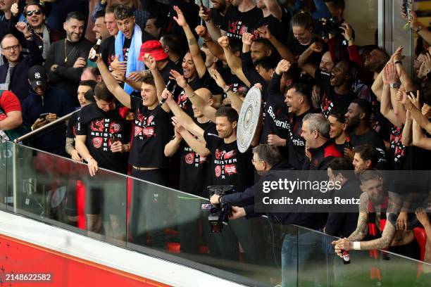 Xabi Alonso, Head Coach of Bayer Leverkusen, celebrates with a replica trophy alongside players after their team's victory and winning the Bundesliga...