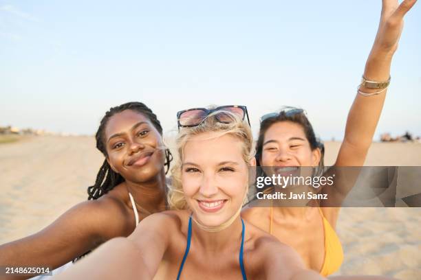 happy group of young multiethnic women friends in bikinis take a selfie with their mobile phones on the beach while enjoying a day of summer holidays. - happy holidays around the world stock pictures, royalty-free photos & images