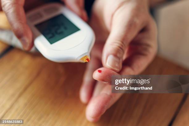 mature man preparing to measure blood glucose level with a glucometer - glucose stockfoto's en -beelden