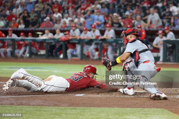 Catcher Ivan Herrera of the St. Louis Cardinals attempts to tag Christian Walker of the Arizona Diamondbacks as he scores a run during the fifth...