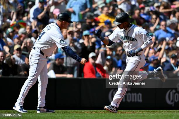 Jorge Polanco of the Seattle Mariners celebrates his two-run home run with third base coach Manny Acta during the seventh inning against the Chicago...