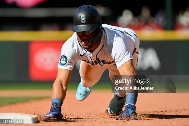 Julio Rodriguez of the Seattle Mariners dives back to first base against the Chicago Cubs during the ninth inning at T-Mobile Park on April 14, 2024...