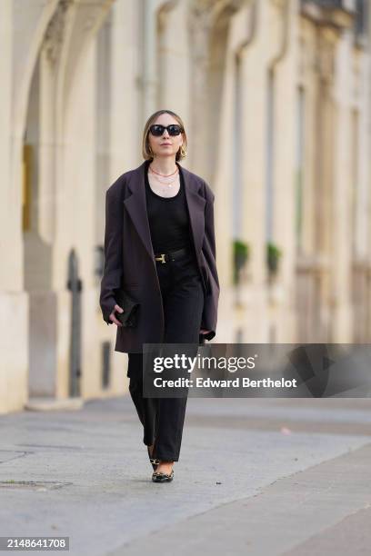 Emy Venturini wears sunglasses, golden earrings, a necklace , a black top from COS, a purple oversize blazer jacket from The Frankie Shop, a Hermes...