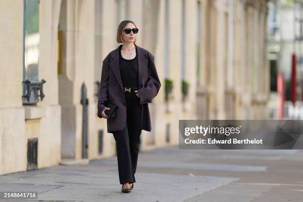 Emy Venturini wears sunglasses, golden earrings, a necklace , a black top from COS, a purple oversize blazer jacket from The Frankie Shop, a Hermes...