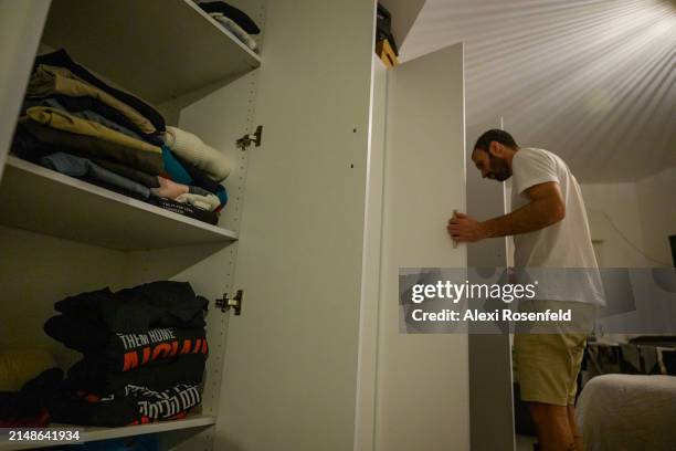 Daniel Lifshitz pulls items from his closet near a stack of "bring them home" sweatshirts while packing a suitcase on April 1, 2024 in Tel Aviv,...