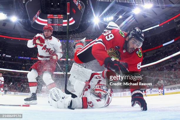Andreas Athanasiou of the Chicago Blackhawks is tripped by Pyotr Kochetkov of the Carolina Hurricanes during the third period at the United Center on...
