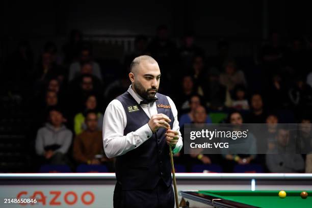 Hossein Vafaei of Iran chalks the cue in the third round match against Marco Fu of Chinese Hong Kong on day seven of 2024 World Championship...