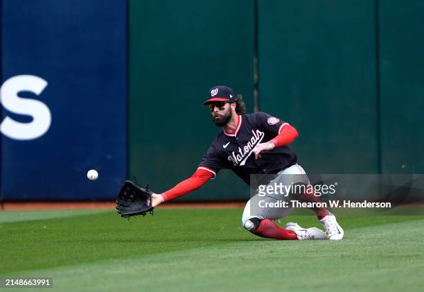 Jesse Winker of the Washington Nationals dives for a ball that falls for a hit from JJ Bleday of the Oakland Athletics in the bottom of the first...