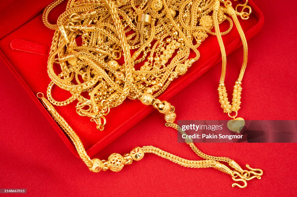 Gold necklaces in a red velvet box on a red textile.