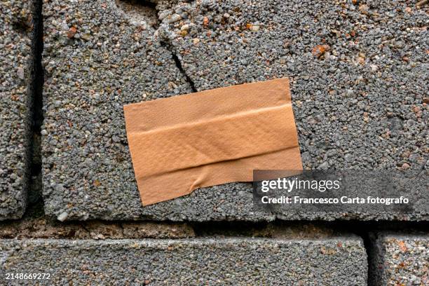 crack in cement wall with band aid - misserfolg stock-fotos und bilder