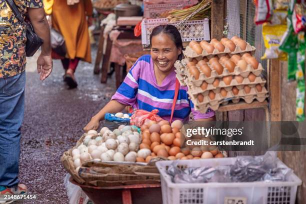 happy woman selling eggs in the market - indonesian culture stock pictures, royalty-free photos & images