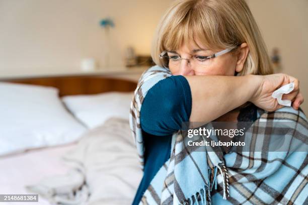 femme âgée avec toux assise dans son lit - tousser photos et images de collection