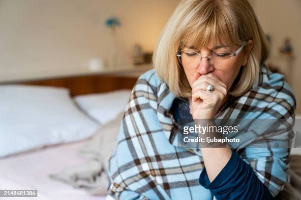 senior woman coughing after wake up on bed - flatten the curve imagens e fotografias de stock
