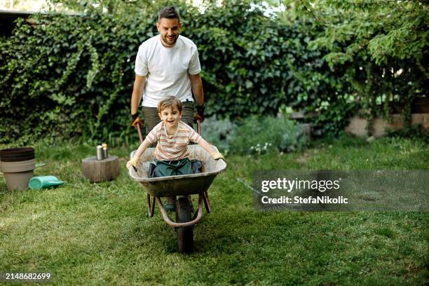 father and child having fun outdoor - kruiwagen stockfoto's en -beelden