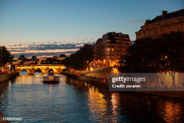 vista romantica sulla riva illuminata del fiume e pont neuf sulla senna a parigi al crepuscolo - fiume senna foto e immagini stock
