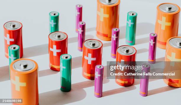 conceptual image of various sized batteries against a white backdrop - lithium stock pictures, royalty-free photos & images