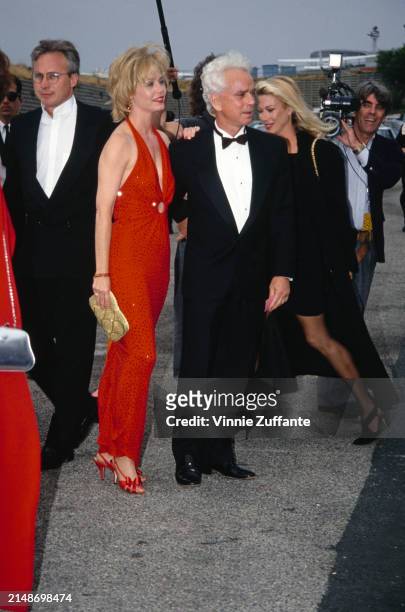 American actress Susan Dey, wearing a full-length red halterneck dress with a plunging neckline, and her husband, American film producer Bernard...