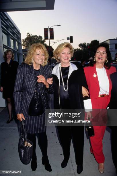 American actress Angie Dickinson, wearing a dark grey pinstripe suit with a black crew-neck top, and American socialite Barbara Sinatra, who wears a...