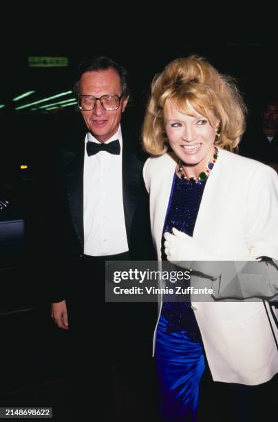 American broadcaster Larry King, wearing a tuxedo and bow tie, and American actress Angie Dickinson, who wears a white coat over a blue sequin dress...