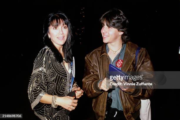 American actress Joyce DeWitt, wearing a black-and-silver outfit, beside a man, who wears a brown leather jacket and a 'People's Choice Awards Press'...