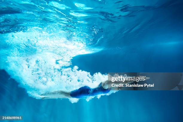 female swimmer in blue swimsuit swimming after the jump, underwater view - swimmers underwater stock pictures, royalty-free photos & images
