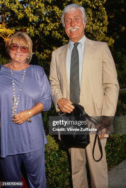 American actress Michelle Triola, wearing a lilac outfit with a long necklace, and American actor and comedian Dick Van Dyke, who wears a beige suit...