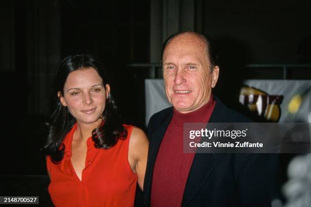 Argentine actress Luciana Pedraza, wearing a red outfit, and American actor Robert Duvall, who wears a black blazer over a red turtleneck sweater,...